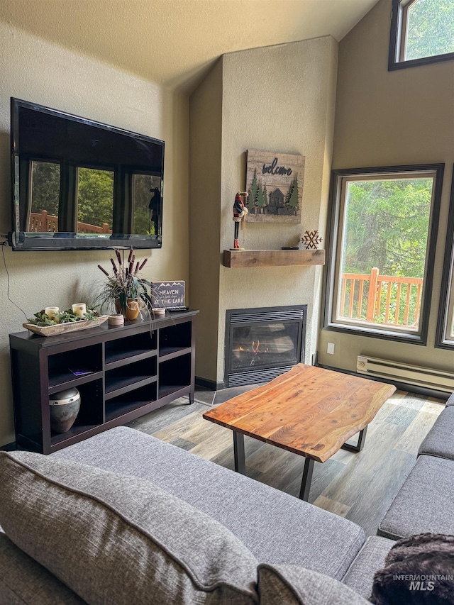 living room with a baseboard heating unit, lofted ceiling, wood-type flooring, and plenty of natural light