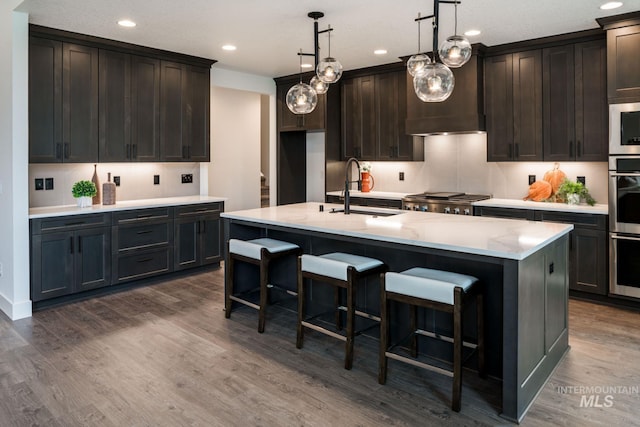 7755 W Flathead Lake St, Eagle, ID 83616 - kitchen featuring a sink, recessed lighting, dark wood-style flooring, a center island with sink, and a breakfast bar area