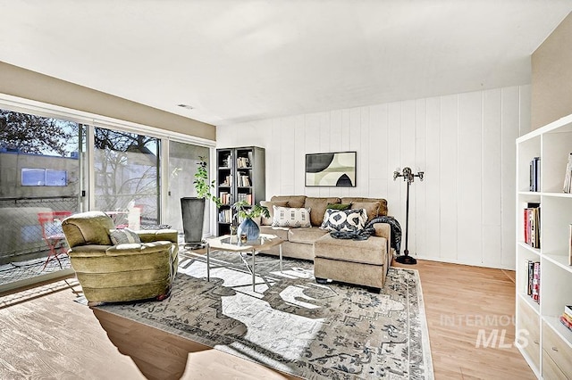 living room featuring light hardwood / wood-style flooring and wooden walls