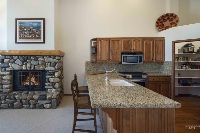 732 Morning Star Rd, Sun Valley, ID 83353 - kitchen with light stone countertops, a breakfast bar, a stone fireplace, stainless steel appliances, and a sink