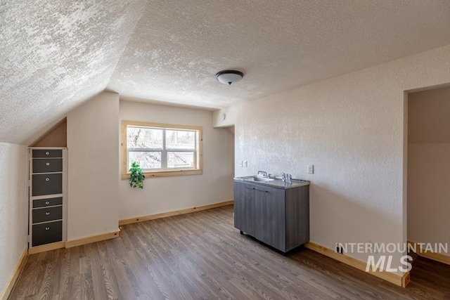 bonus room with vaulted ceiling, a textured ceiling, baseboards, and wood finished floors