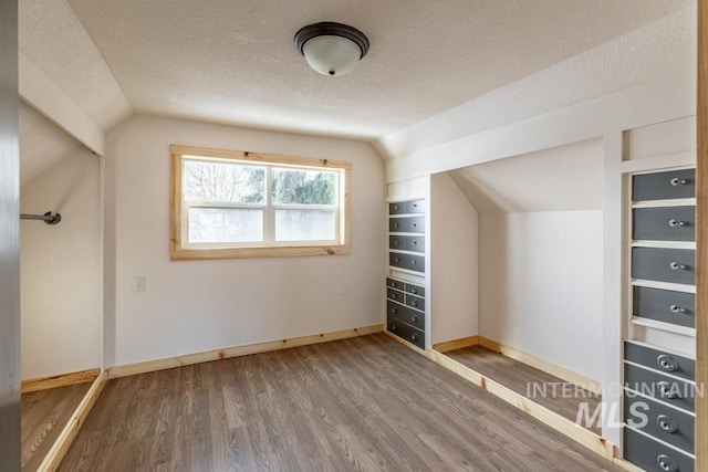 bonus room with lofted ceiling, baseboards, a textured ceiling, and wood finished floors