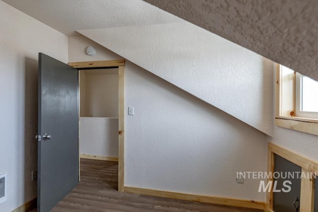 bonus room with visible vents, baseboards, a textured wall, dark wood-style flooring, and a textured ceiling