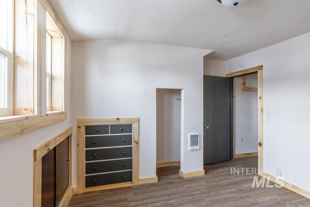 unfurnished bedroom featuring dark wood-style flooring, visible vents, a textured ceiling, and baseboards