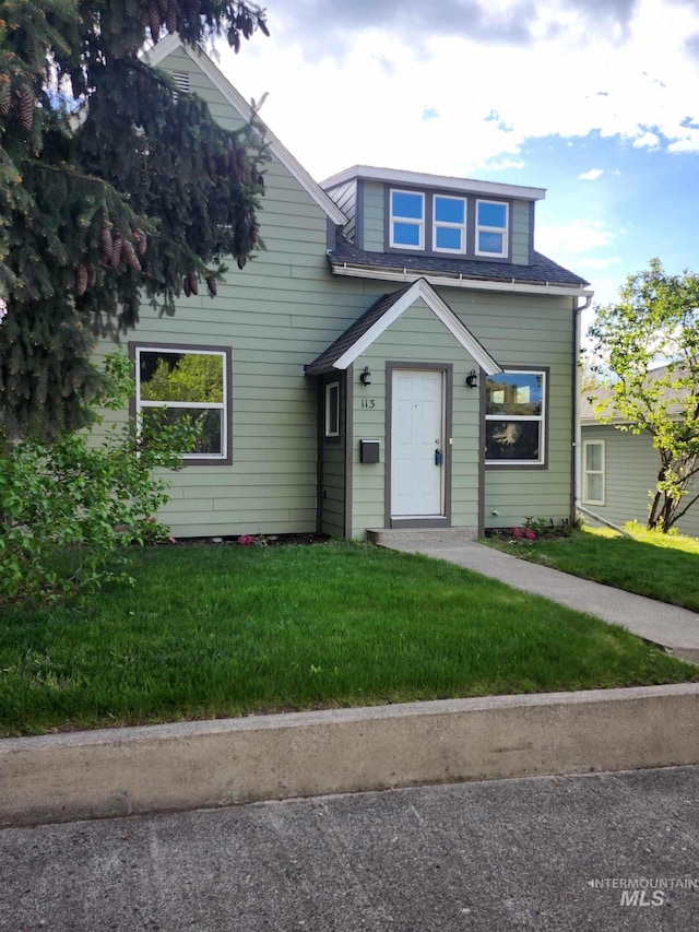 view of front of house featuring a shingled roof and a front lawn