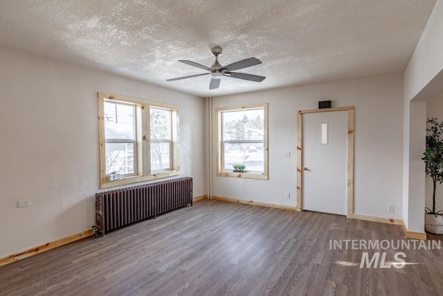 interior space with baseboards, a textured ceiling, radiator heating unit, and wood finished floors