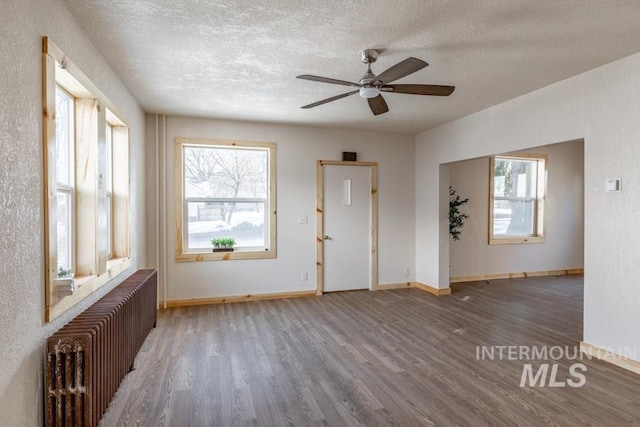 interior space with dark wood-type flooring, radiator, a textured ceiling, and baseboards