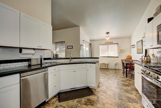 kitchen with tasteful backsplash, sink, stainless steel appliances, lofted ceiling, and white cabinets