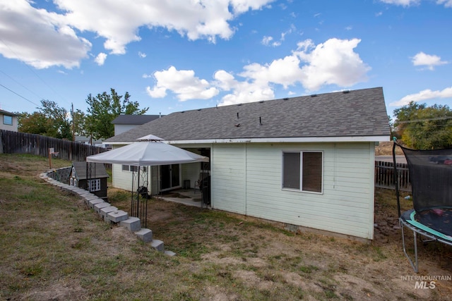 rear view of property with a yard and a trampoline