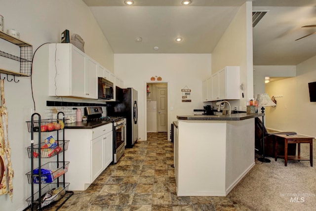 kitchen with dark carpet, appliances with stainless steel finishes, kitchen peninsula, and white cabinetry