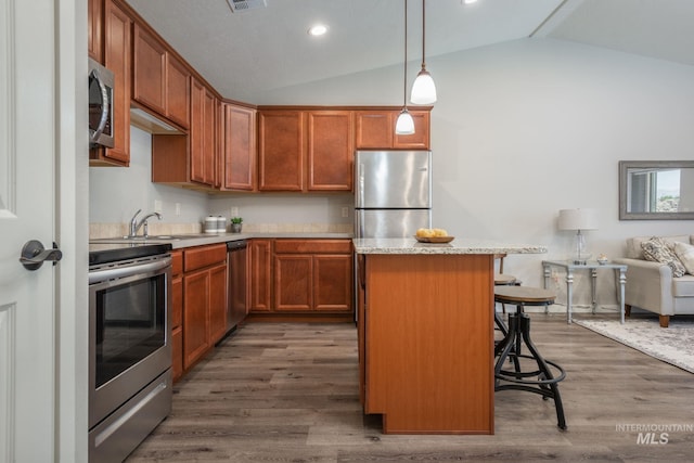 3438 5th St Unit D, Lewiston, ID 83501 - kitchen featuring appliances with stainless steel finishes, vaulted ceiling, a sink, a kitchen island, and a kitchen bar