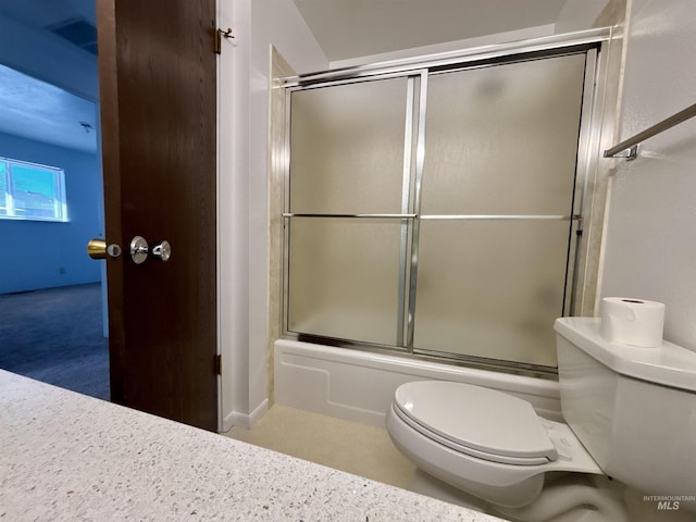 bathroom featuring toilet and shower / bath combination with glass door