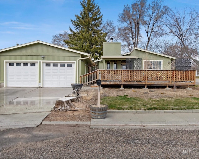 ranch-style home with a wooden deck, concrete driveway, and a chimney