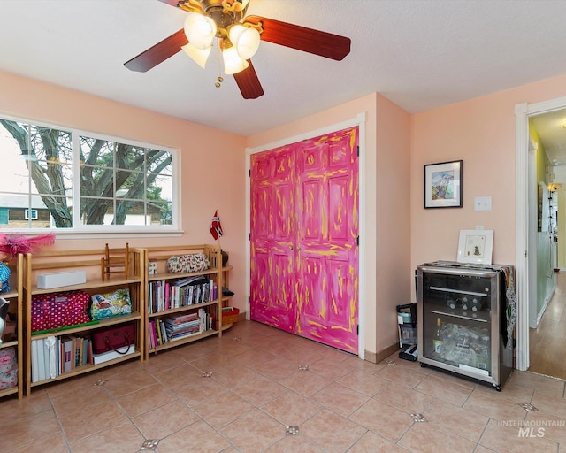 playroom featuring tile patterned floors, wine cooler, and ceiling fan