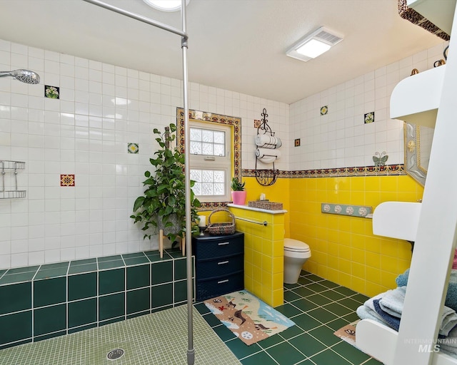 bathroom with tile walls, toilet, tile patterned floors, and tiled shower