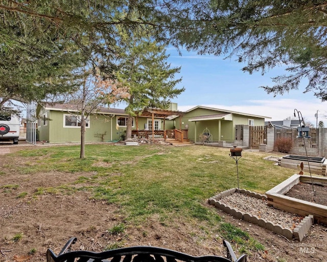 exterior space with a lawn, fence, a deck, and a garden