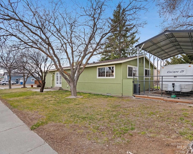 view of side of home with a carport, entry steps, a yard, and fence