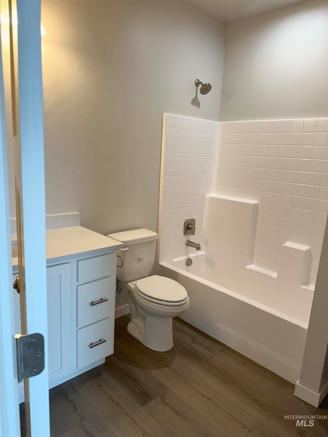 bathroom featuring wood-type flooring, toilet, and shower / washtub combination