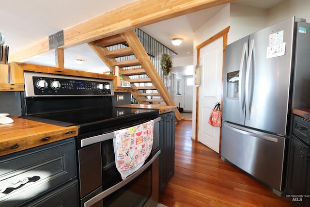 kitchen with dark wood-type flooring, wood counters, stainless steel appliances, and dark cabinetry