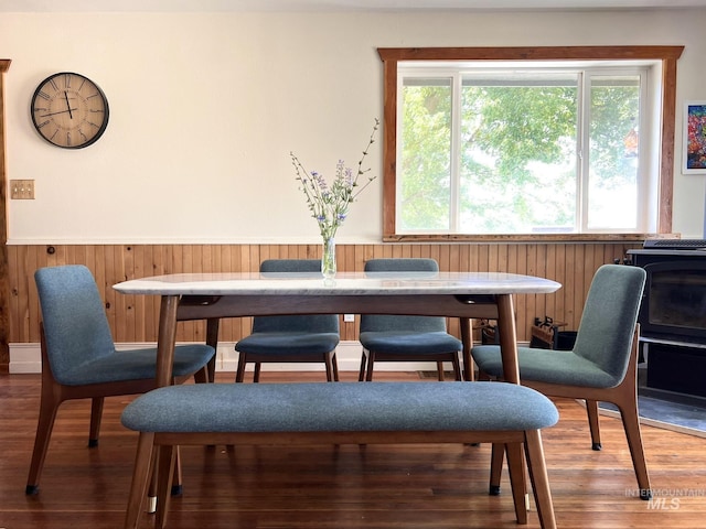 dining area with wooden walls, wood finished floors, and wainscoting