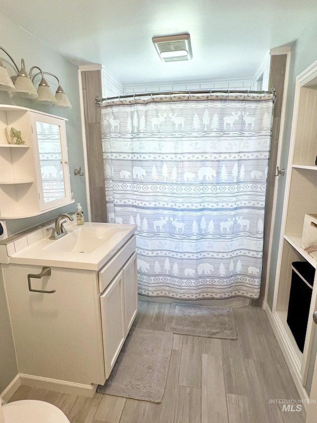 full bathroom with curtained shower, vanity, toilet, and wood finished floors