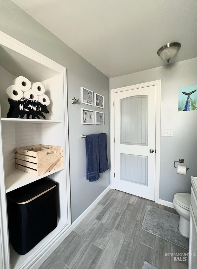 bathroom featuring vanity, wood finished floors, toilet, and baseboards