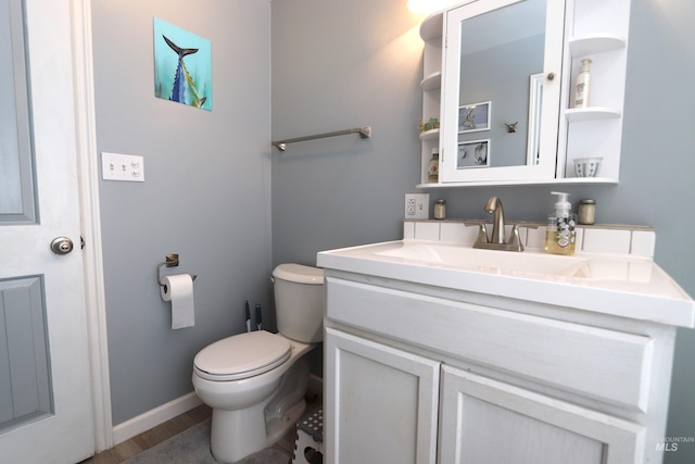 bathroom featuring toilet, baseboards, wood finished floors, and vanity