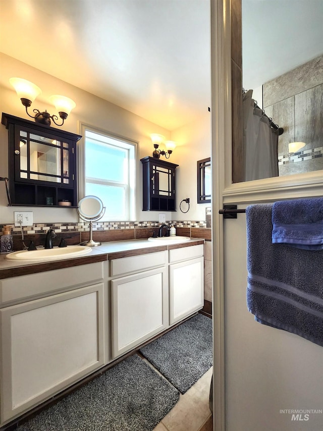 full bathroom featuring double vanity, curtained shower, a sink, and tile patterned floors