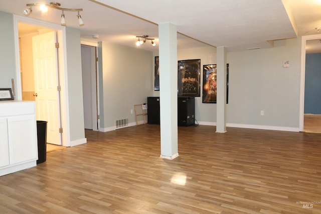 interior space featuring baseboards, track lighting, visible vents, and light wood-style floors