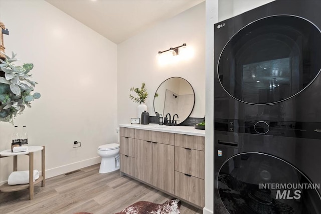 362-436 W London St, Middleton, ID 83644 - bathroom featuring visible vents, toilet, vanity, stacked washing maching and dryer, and wood finished floors
