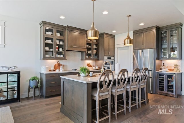 12013 W Zamalek Ct, Kuna, ID 83634 - kitchen featuring appliances with stainless steel finishes, light countertops, beverage cooler, tasteful backsplash, and dark wood-type flooring