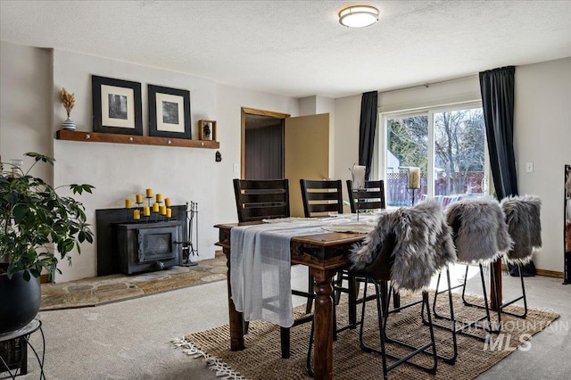 carpeted dining space featuring a textured ceiling and a wood stove