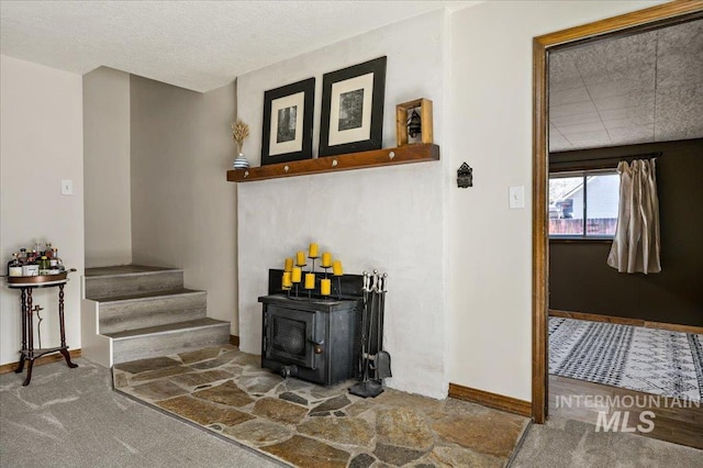 interior space with a wood stove, carpet flooring, and baseboards