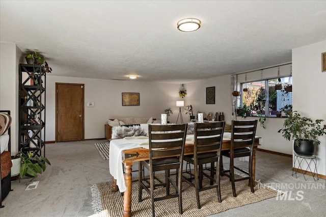 dining space featuring baseboards, carpet floors, and a textured ceiling