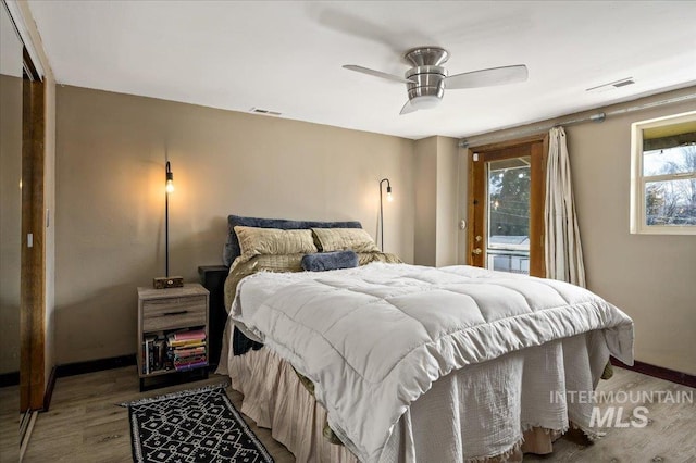 bedroom featuring visible vents, baseboards, ceiling fan, and wood finished floors