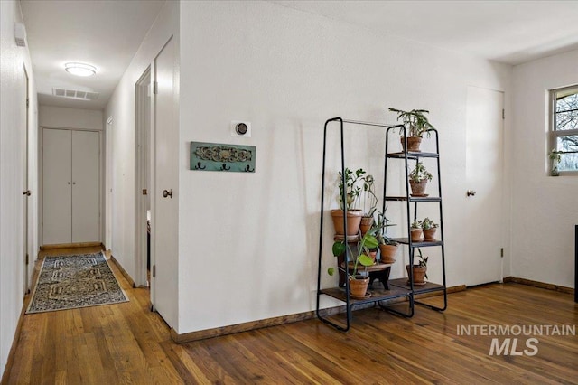 hallway with visible vents, baseboards, and wood finished floors