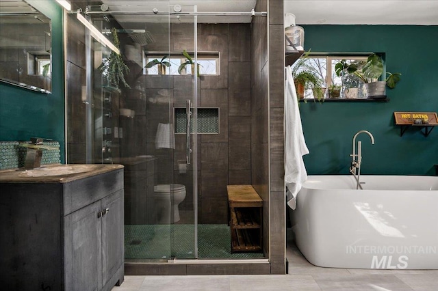 full bath featuring a stall shower, vanity, and a freestanding tub