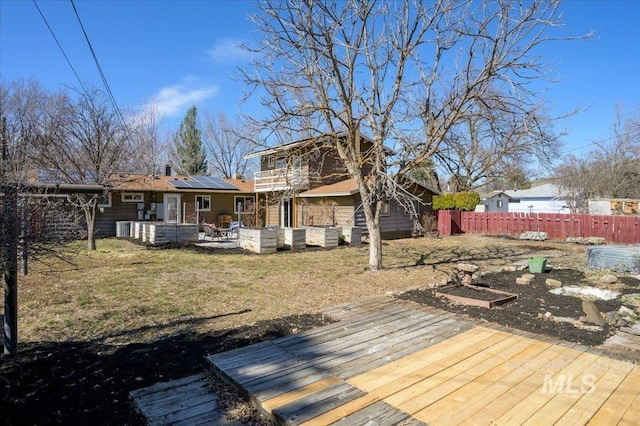 rear view of property with a patio, fence, solar panels, central AC, and a deck