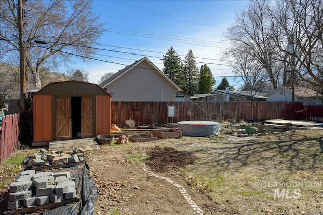 view of yard with a garden, an outbuilding, a fenced backyard, and a shed