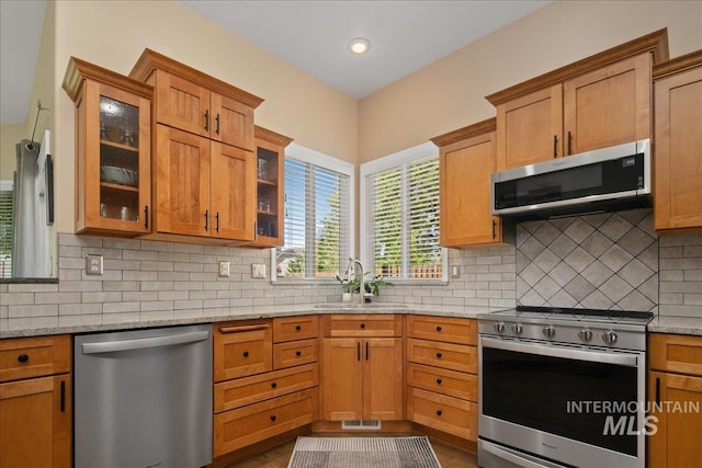 1049 N Purple Sage Way, Eagle, ID 83616 - kitchen featuring appliances with stainless steel finishes, light stone countertops, backsplash, glass insert cabinets, and recessed lighting