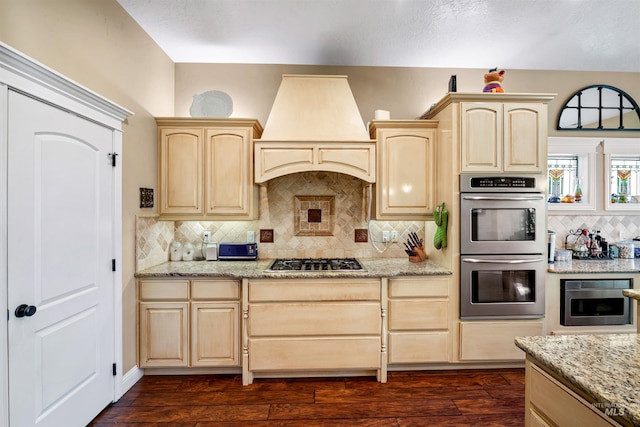 4965 S Nickel Creek Ave, Meridian, ID 83642 - kitchen featuring light brown cabinets, light stone counters, custom exhaust hood, tasteful backsplash, and appliances with stainless steel finishes