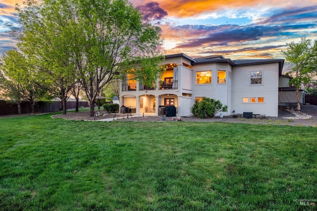 4965 S Nickel Creek Ave, Meridian, ID 83642 - back of house at dusk with a patio, stucco siding, fence, a balcony, and a yard