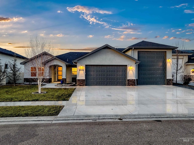 view of front of home with stucco siding, stone siding, a yard, concrete driveway, and an attached garage