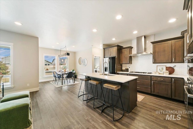 kitchen with backsplash, wall chimney exhaust hood, stainless steel fridge with ice dispenser, and light countertops