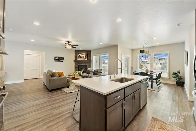 kitchen featuring a sink, a healthy amount of sunlight, light wood-style flooring, and a fireplace