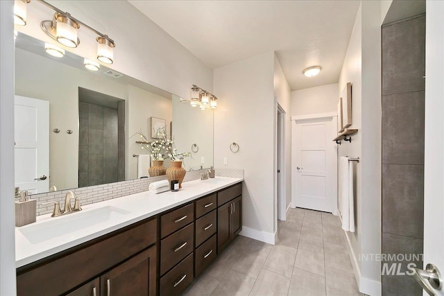 full bathroom with a sink, baseboards, double vanity, and tile patterned floors