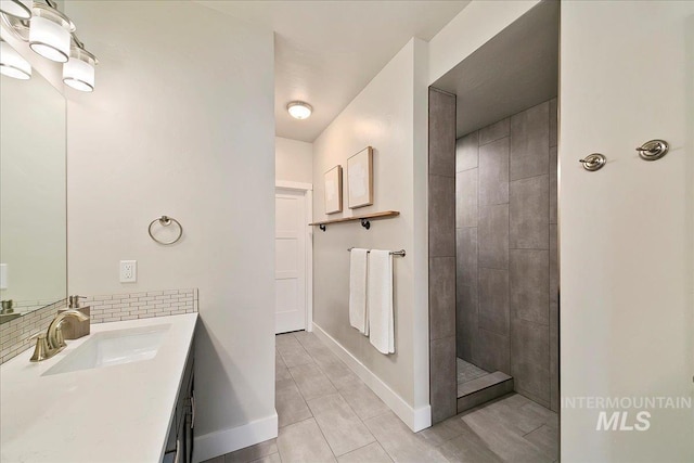 bathroom featuring decorative backsplash, a walk in shower, vanity, and baseboards