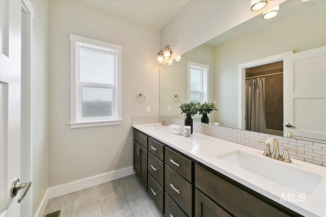 bathroom featuring tile patterned floors, baseboards, backsplash, and a sink