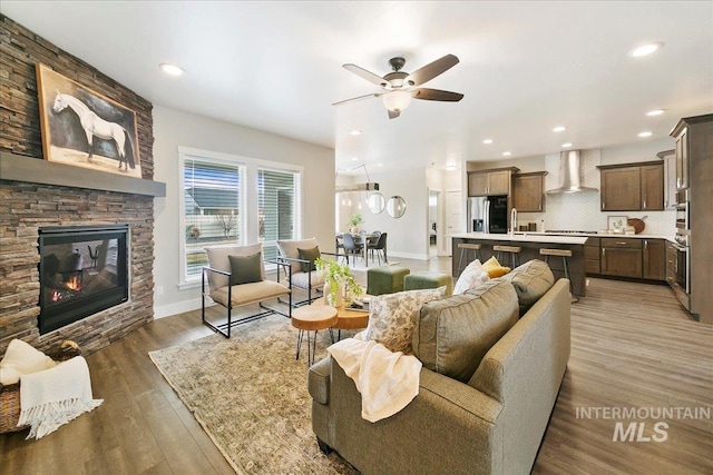 living area with recessed lighting, baseboards, light wood-style floors, and a stone fireplace