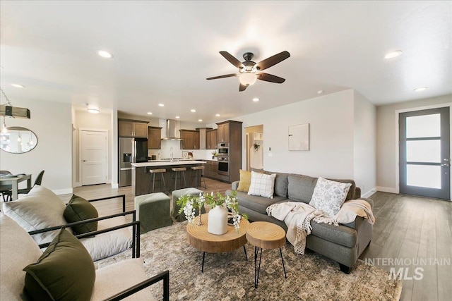 living room featuring recessed lighting, baseboards, light wood-style flooring, and a ceiling fan